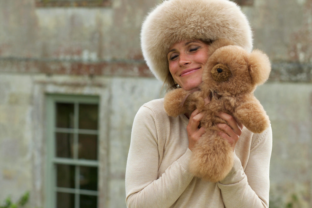 Woman wearing a fur hat and holding an Alpaca Fur teddy bear