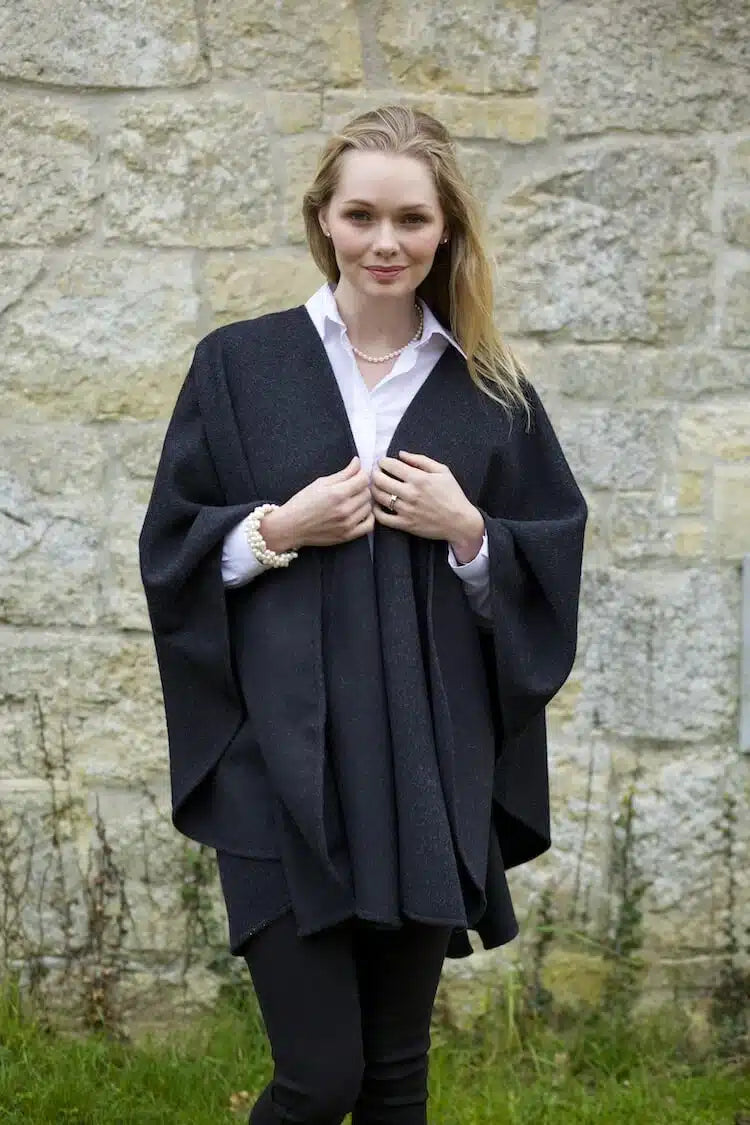 Grey and black Lacorine classic alpaca wool cape draped over shoulders, showcasing soft, luxurious fabric and stylish design.