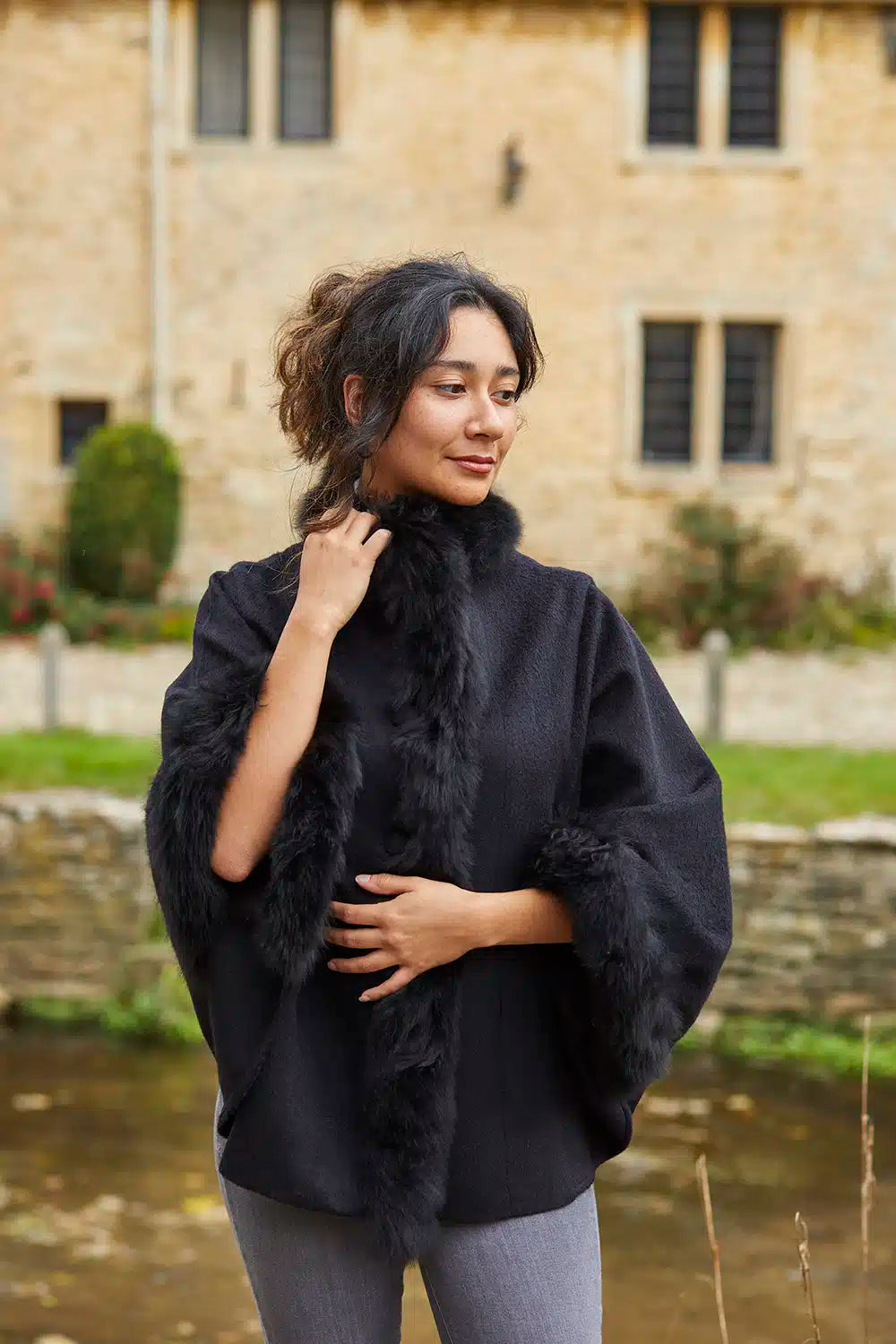 Black alpaca poncho with fur trim from Lacorine, showcasing a cozy, stylish garment with a soft fur-lined collar and draped fit.