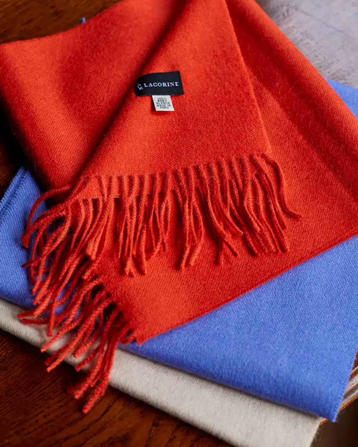 Lacorine fine alpaca knit scarf in soft, warm beige with subtle ribbed texture, draped to showcase its cozy, luxurious fabric.